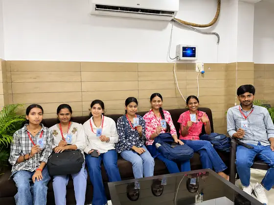 Seven students sitting along the sofa at the training centre, holding up their new ID cards