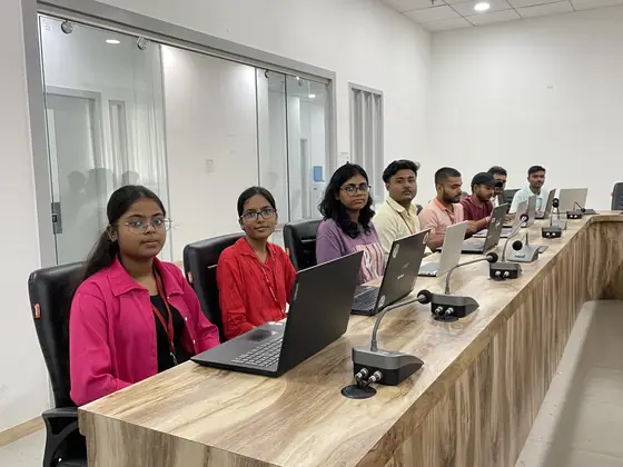 Students working at laptops around the bench in the Softpro training room