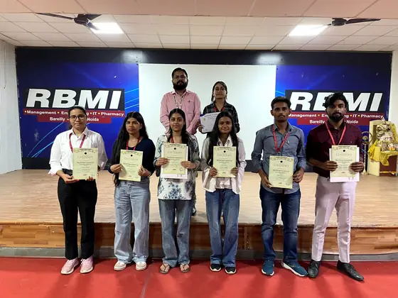 Six students standing on stage with their certificates in front of the event backdrop