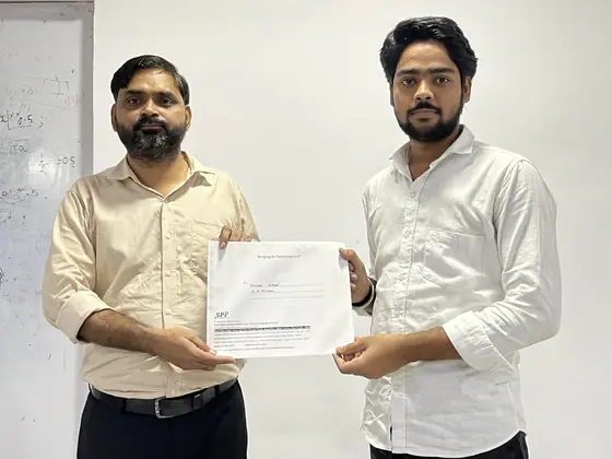 A trainer handing a certificate to a student, both holding it for the photograph