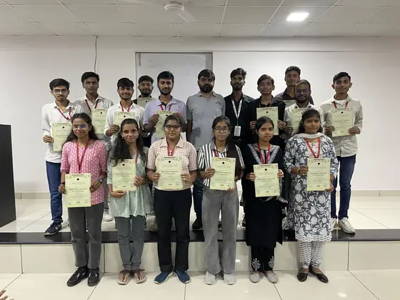 A batch of eleven students on stage holding their certificates