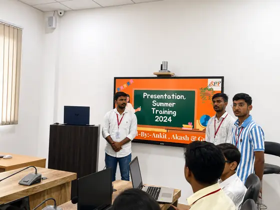 Three students presenting their summer training project on a classroom smart board