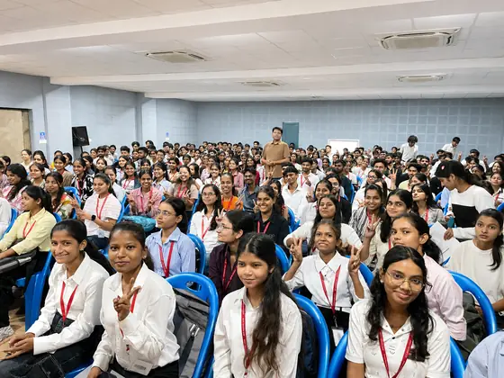 The front rows of a packed college hall, students turned towards the camera and smiling