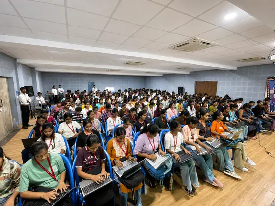 Students following the session on open laptops, notebooks balanced on their knees