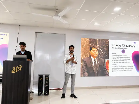 A student at the microphone introducing the Director of Softpro India from a slide on screen