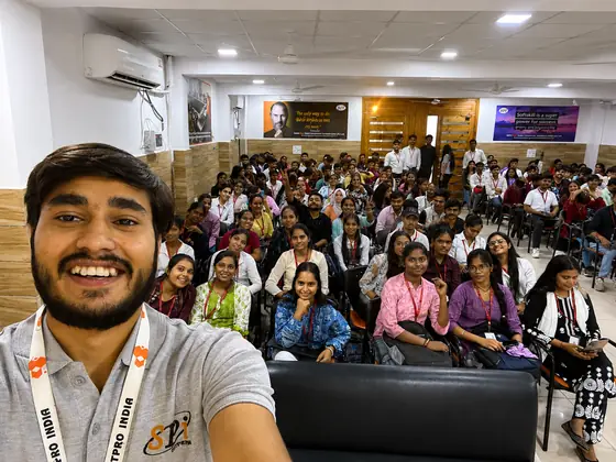 A Softpro trainer taking a selfie with a hall of students filling the frame behind