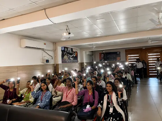 Wide view of a darkened hall lit by rows of raised phone torches