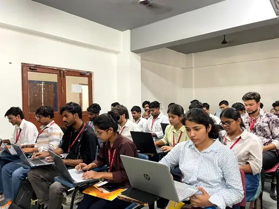 Students working on laptops in a lecture hall during a coding session