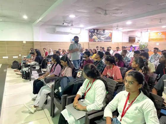 Students seated along the side of a hall listening to the session