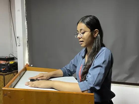 A student speaking from a wooden lectern during a session