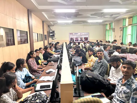 Wide view of a full computer lab, students at benches running along the room