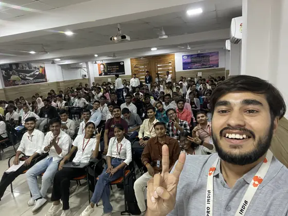 A Softpro trainer taking a selfie at the front of a hall, the whole batch behind him with hands raised