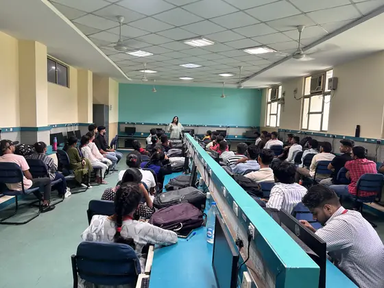 A computer lab with teal benches, students seated at terminals during a session