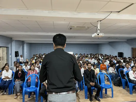 A trainer seen from behind facing a full hall of seated students
