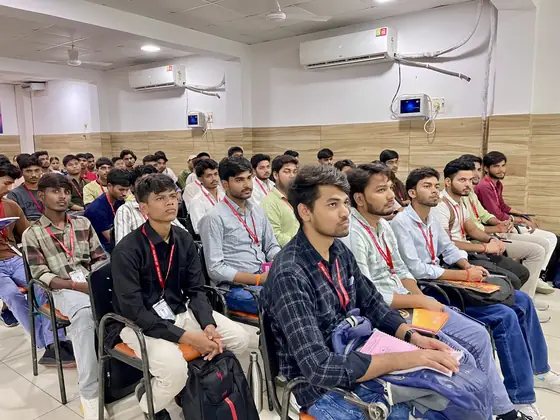 Students seated in a hall during an evening session, lanyards on
